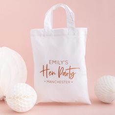 a white tote bag with hen party lettering on it next to some paper balls