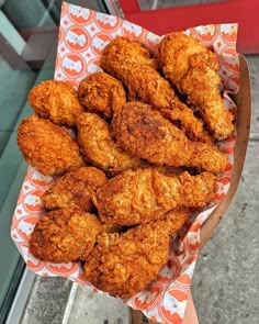 fried chicken sticks are piled on top of each other in a paper tray with an orange and white pattern