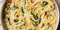 a pan filled with pasta and spinach on top of a table