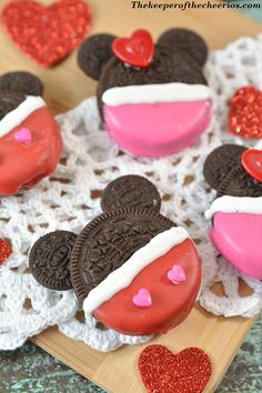 minnie mouse oreo cookies with pink frosting and red hearts on a wooden board