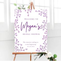 the welcome sign is displayed on an easel with flowers in it and greenery