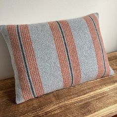 an orange and grey striped pillow sitting on top of a wooden table