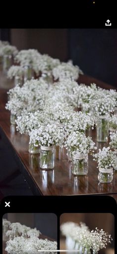 several vases filled with white flowers sitting on top of a wooden table next to each other