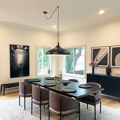 the dining room table is surrounded by modern chairs and art on the wall behind it