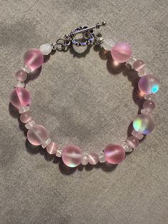 Made with Pink Mermaid Glass style beads. Moonstones and pink cat's eye beads in between bigger beads. It was wire and has a silver color toggle. I added an extender. It is now 9 inches long with the extender. Pink Czech Glass Bracelets With Spacer Beads, Pink Wire Wrapped Beaded Bracelets With Round Beads, Handmade Pink Glass Bracelets, Handmade Pink Moonstone Jewelry, Pink Beaded Glass Bracelets, Pink Glass Beaded Bracelets, Adjustable Pink Glass Beaded Bracelets, Mermaid Glass, Pink Mermaid