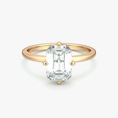 an emerald cut diamond engagement ring with three clawed shans on the band and shoulders