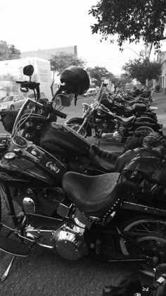 a row of motorcycles parked next to each other on the side of a road in black and white