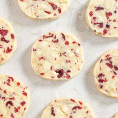 several cookies with cranberry toppings are arranged on a baking sheet and ready to be baked