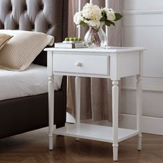 a white nightstand table with flowers on it