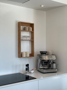 an espresso machine sitting on top of a counter next to a wooden shelf