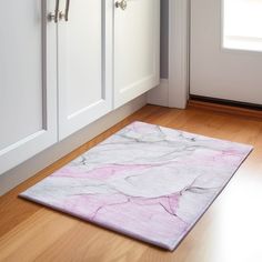 a pink and white rug on the floor in front of some cupboards with doors