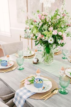 a table set for easter with flowers and eggs