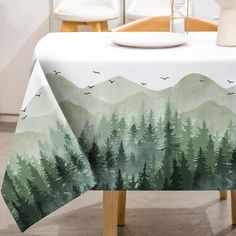 a table with a forest scene on it and birds flying over the mountains in the distance