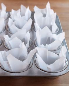 muffin tins filled with white paper on top of a wooden table