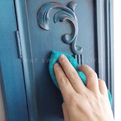 a person wiping up the handle on a blue door with a microfiber cloth