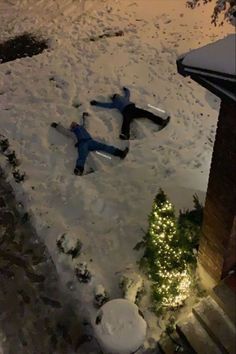 two people laying in the snow on their stomachs