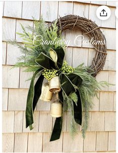 a christmas wreath hanging on the side of a building with bells and greenery around it