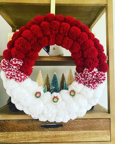 a christmas wreath with red and white pom - poms