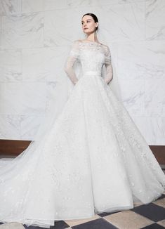 a woman in a white wedding dress standing on a checkered floor with her arms behind her back