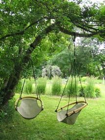 two hammocks hanging from a tree in a park