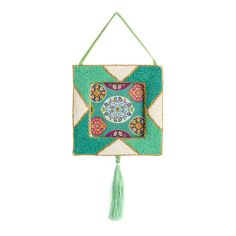 a green and white wall hanging with a tassell on the end of it