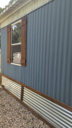 the side of a house with a metal siding and wooden window panes on it