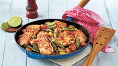 a pan filled with chicken and vegetables on top of a wooden table