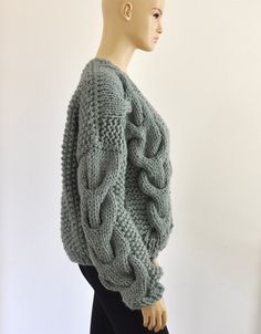 a mannequin wearing a green sweater and black leggings stands in front of a white wall