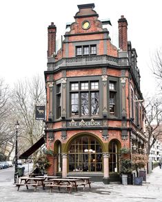 an old brick building with a clock on it's side and benches in front