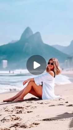 a woman sitting on top of a sandy beach