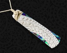 a white and blue object hanging from a rope on a black background with intricate designs