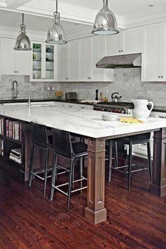 a large kitchen with an island in the middle and two bar stools at the end