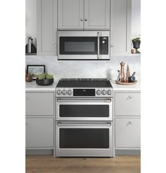 a stainless steel stove and microwave in a kitchen with gray cabinets, white counter tops and wood flooring