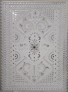 an intricately designed white tile with decorative designs on the outside and inside, is displayed