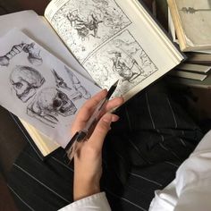 a person is holding an open book with drawings on it and writing something in front of them