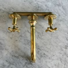 two golden handles on a marble counter top with gold fittings and knobs in the middle