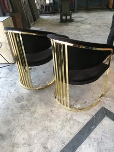 two black and gold chairs sitting on top of a marble floor next to each other