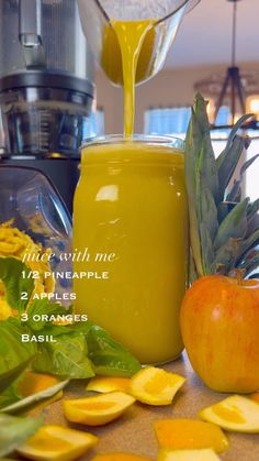 an orange juice is being poured into a jar with sliced apples and other fruits around it