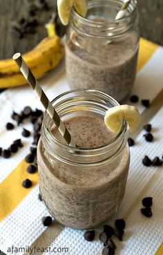 two mason jars filled with chocolate banana smoothie and topped with bananas on the side