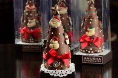 three chocolate christmas trees in glass cases on a table