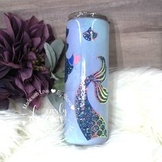 a purple flower and a blue water bottle sitting on a white fur covered floor next to a wooden wall