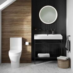 a white toilet sitting next to a bathroom sink under a round mirror on a wall