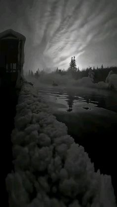 a train traveling down tracks next to a body of water with clouds in the sky