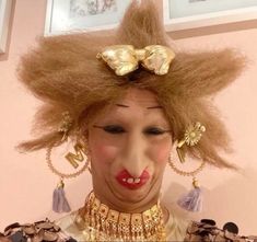 a woman with long blonde hair and gold jewelry on her head is making a funny face