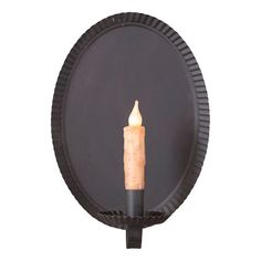 a lit candle sitting on top of a round black wall mounted holder with an inner circle