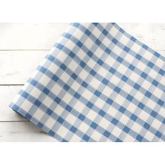 the blue and white checkered fabric is folded on top of a wooden tablecloth