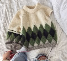 a person sitting on top of a bed next to a white blanket and a sweater