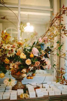 a vase filled with lots of flowers sitting on top of a table covered in cards