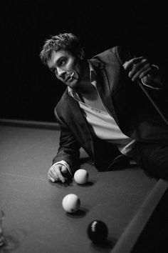 a man in a suit leaning over a pool table with three balls on the table