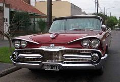 an old red car is parked on the street